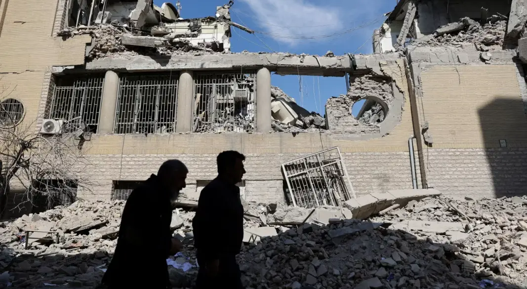 তেহরানে একটি পুলিশ স্টেশনে হামলার পর ক্ষতিগ্রস্ত ভবনের পাশ দিয়ে হেঁটে যাচ্ছেন মানুষ | ছবি : রয়টার্স